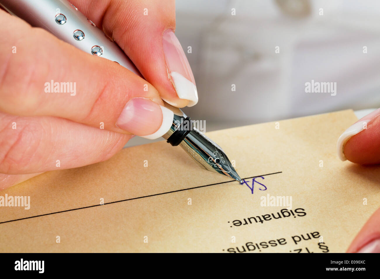 A woman signs a contract or a testament with a fountain-pen., Eine Frau unterschreibt einen Vertrag oder ein Testament mit einer Stock Photo