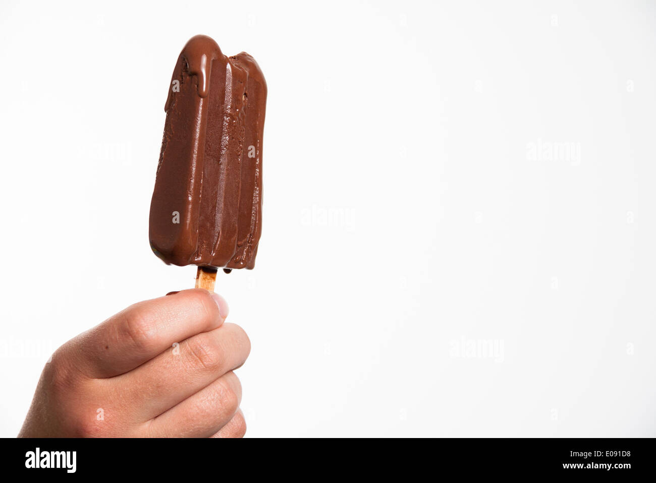 Hand of a teenage girl holding a chocolate ice cream bar Stock Photo