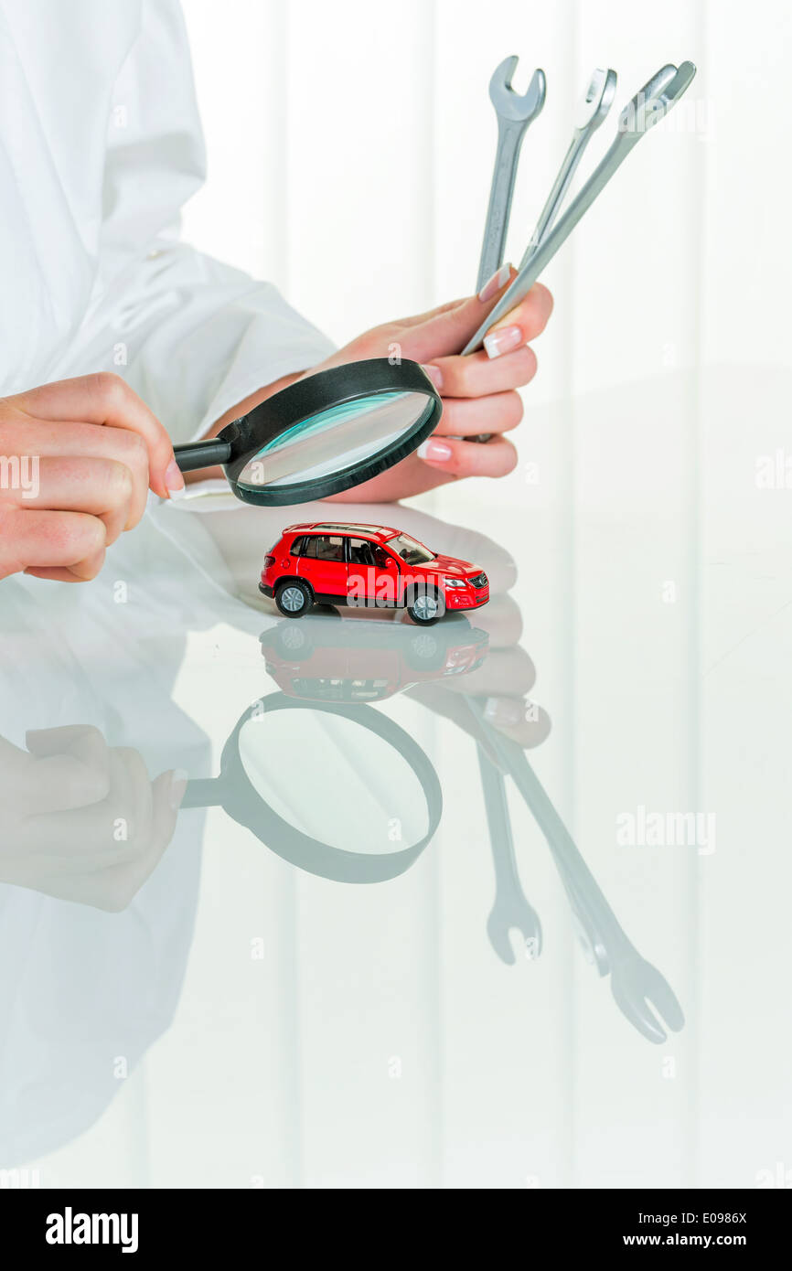 A model of a car is examined by a doctor. Symbolic photo for workshop, service and autopurchase., Ein Modell eines Autos wird vo Stock Photo
