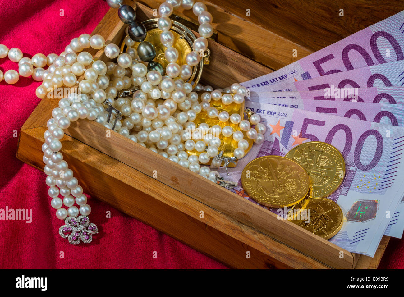 Gold in coins and ingots with jewellery on red velvet. Symbolic photo fue wealth, luxury, Imperial-expensive., Gold in Muenzen u Stock Photo