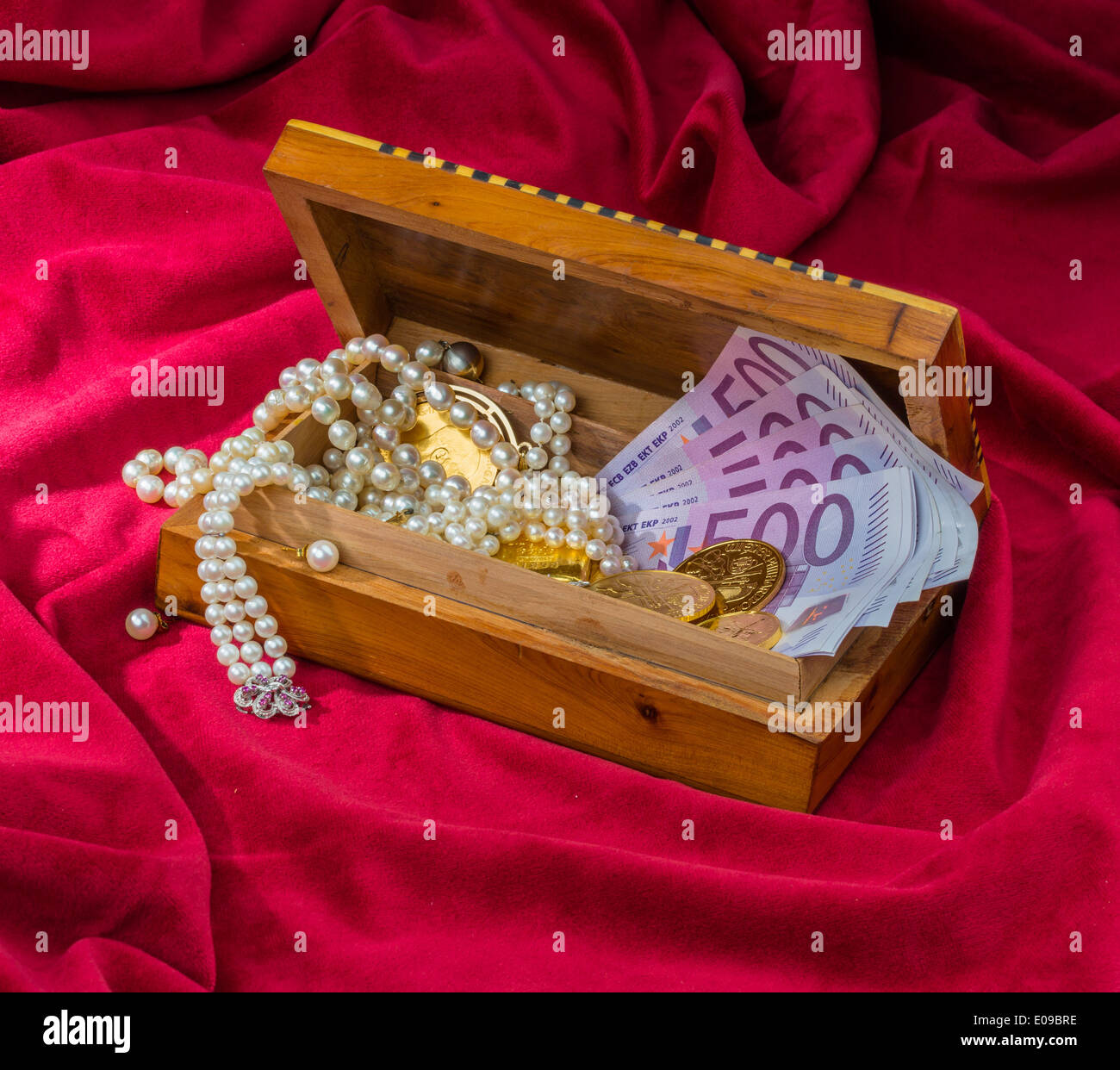 Gold in coins and ingots with jewellery on red velvet. Symbolic photo fue wealth, luxury, Imperial-expensive., Gold in Muenzen u Stock Photo