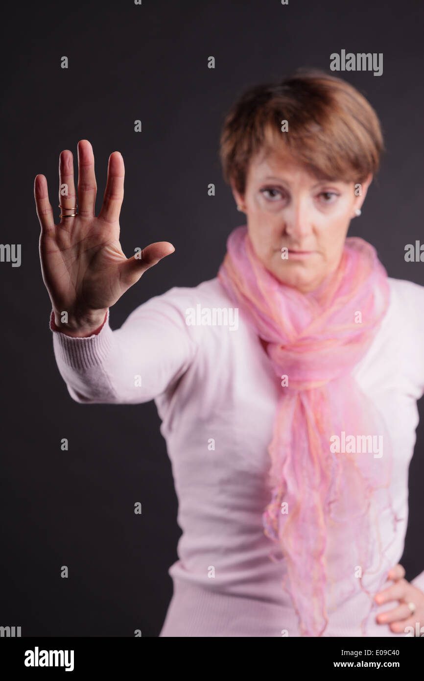 mature woman with a raised hand meaning you can't go further: her hand is open Stock Photo