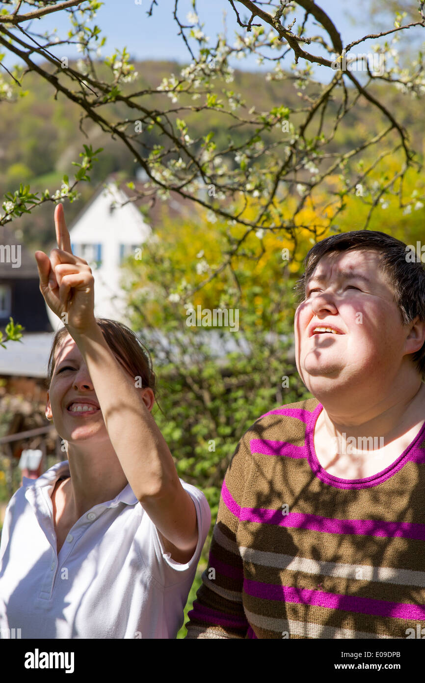 care giver and metaly disabled woman at a plum tree Stock Photo