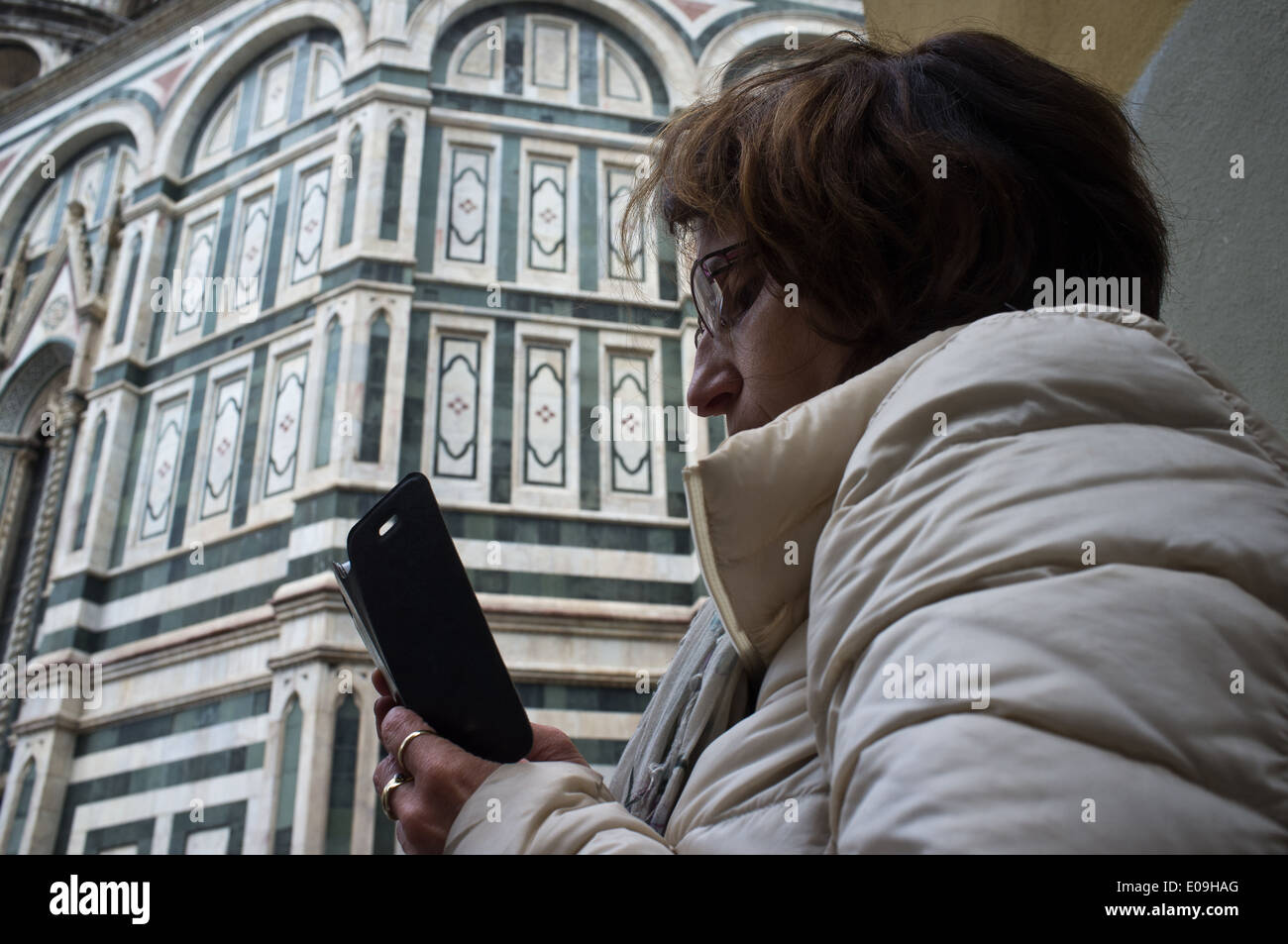 A woman uses a smart phone with the Florence Cathedral in the background. Stock Photo