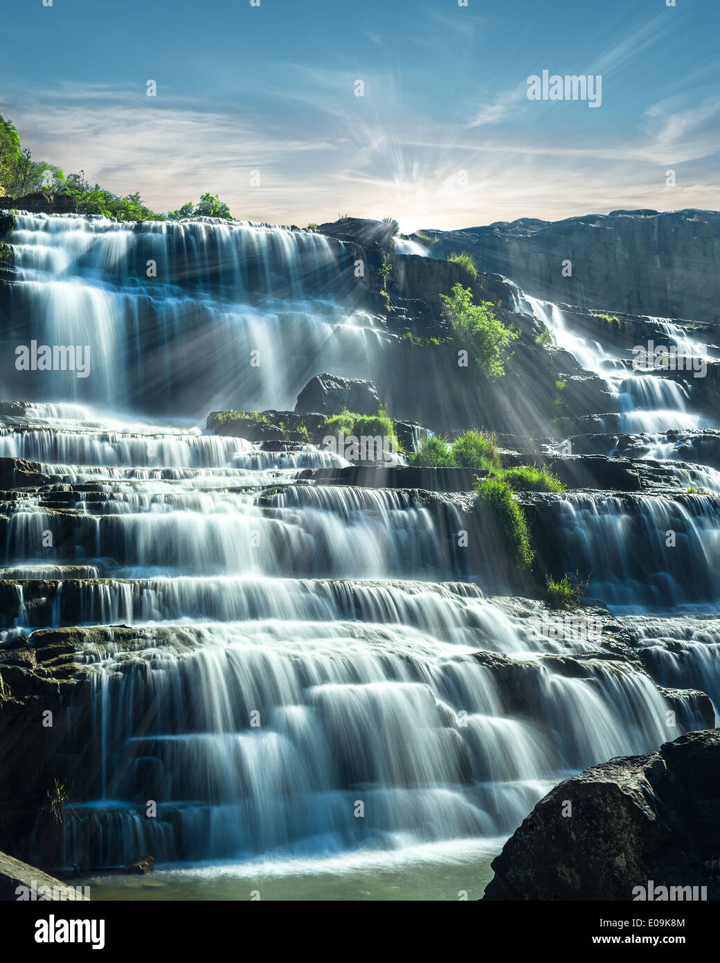 Tropical rain forest landscape with flowing blue water of Pongour waterfall at sunny day under blue sky. Da Lat, Vietnam Stock Photo