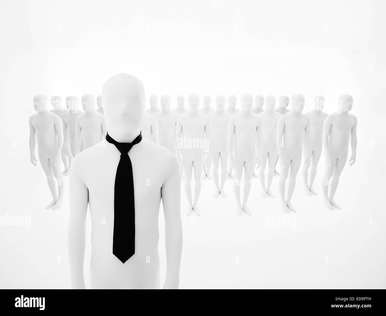 leading man dressed in white with black tie, with white mannequins arranged in multiple rows in background Stock Photo