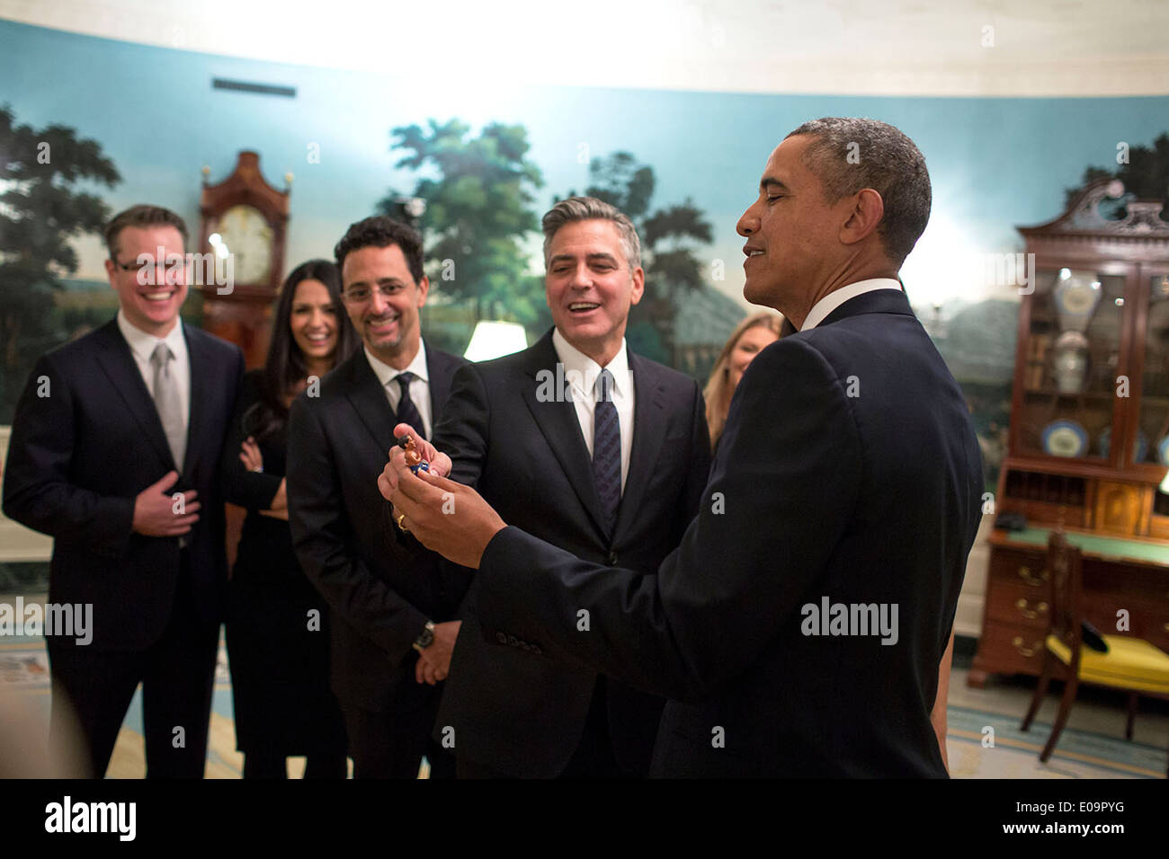 US President Barack Obama jokes with cast members of the movie The Monuments Men in the Diplomatic Reception Room prior to a movie screening in the Family Theater of the White House February 18, 2014 in Washington, DC. Standing from left are: Matt Damon and his wife Luciana Damon, Grant Heslov, and George Clooney. Stock Photo