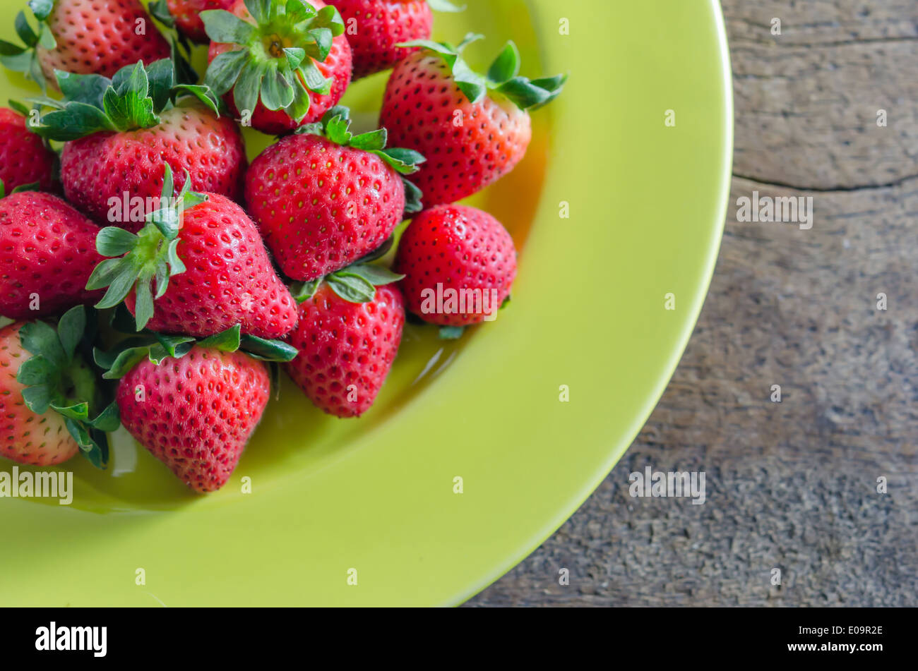 still life of fresh red strawberries on dish over wooden background ...