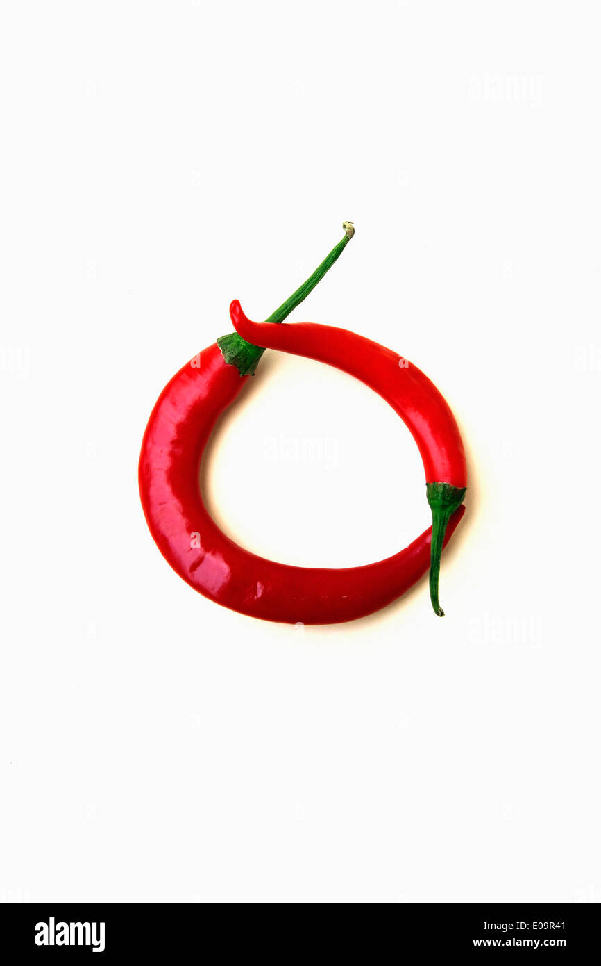 Red peppers shaped like letter O in front of white background Stock Photo