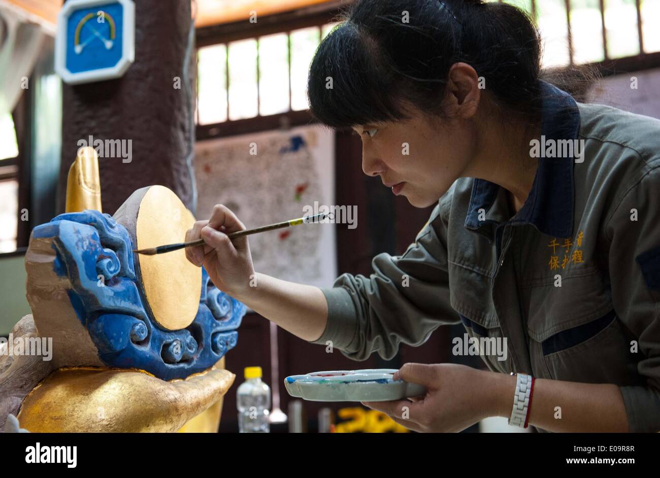 (140507) -- CHONGQING, May 7, 2014 (Xinhua) -- A staff member works during a restoration for a sculpture of Qianshou Guanyin (bodhisattva with a thousand hands) on Mount Baoding in Dazu District in the municipality of Chongqing, southwest China, May 7, 2014. The sculpture, carved in the cave with 7.7 meters high and 12.5 meters wide, could date back to Southern Song Dynasty (1127 to 1279). Over the centuries, the sculpture's color has faded, parts of the gold foil covering have peeled off, and cracks have appeared. And thus, a restoration project for the Buddhist statue has been launched since Stock Photo