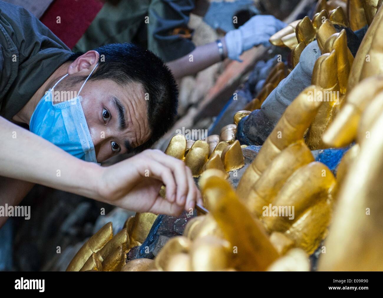 (140507) -- CHONGQING, May 7, 2014 (Xinhua) -- A staff member works during a restoration for a sculpture of Qianshou Guanyin (bodhisattva with a thousand hands) on Mount Baoding in Dazu District in the municipality of Chongqing, southwest China, May 7, 2014. The sculpture, carved in the cave with 7.7 meters high and 12.5 meters wide, could date back to Southern Song Dynasty (1127 to 1279). Over the centuries, the sculpture's color has faded, parts of the gold foil covering have peeled off, and cracks have appeared. And thus, a restoration project for the Buddhist statue has been launched since Stock Photo