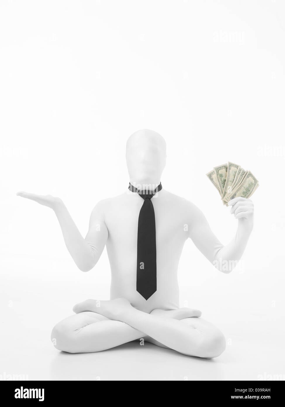 Unknown person standing in lotus position dressed in white suit with black tie holding dollar bills Stock Photo