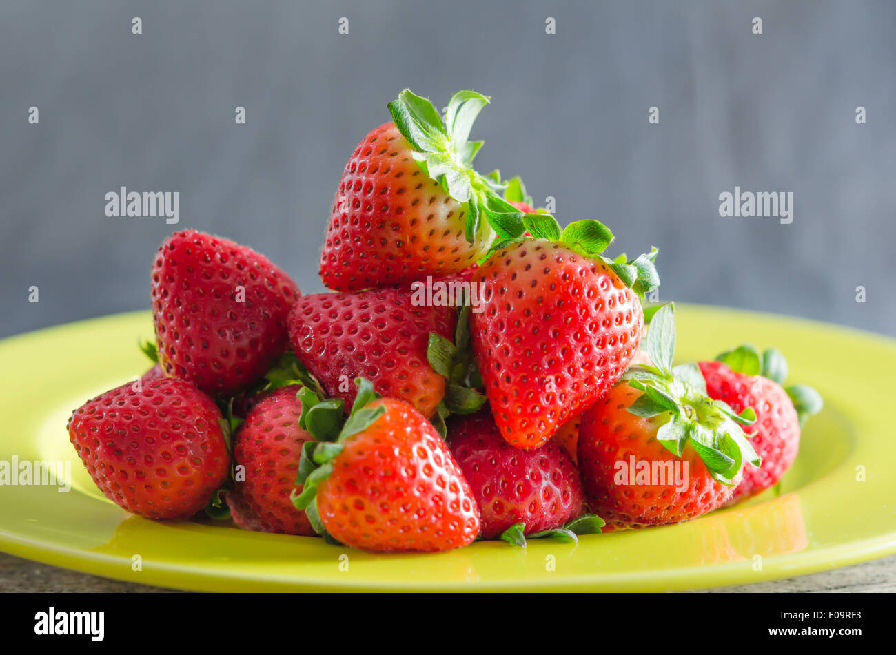 still life of fresh red strawberries on dish over wooden background ...