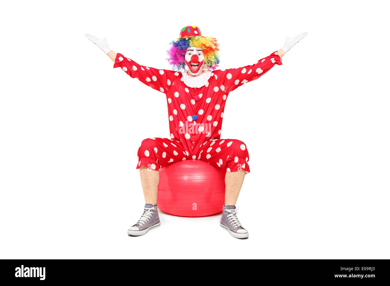 Overjoyed clown sitting on a fitness ball Stock Photo