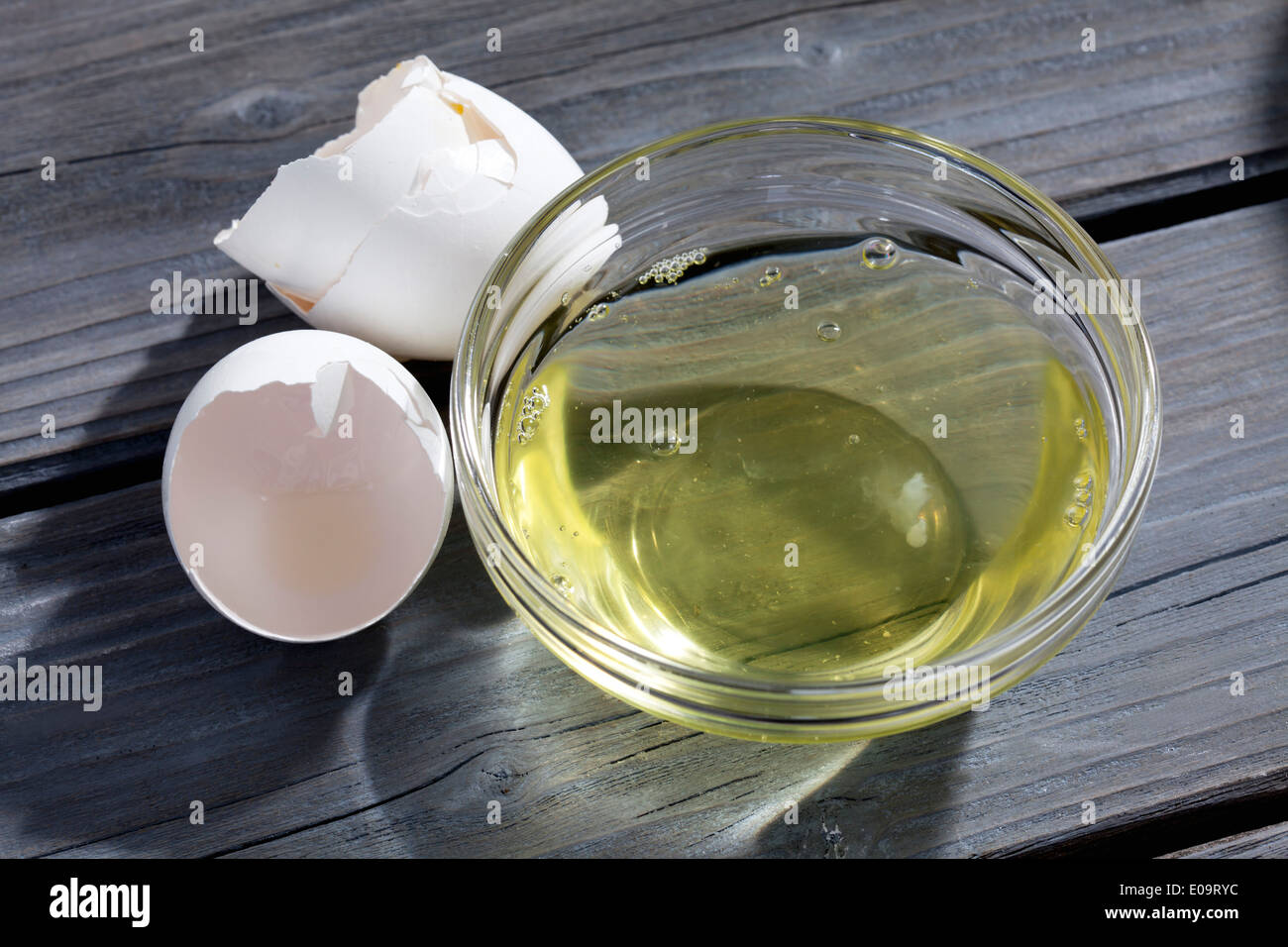 Bowl of egg white and eggshells on grey wood Stock Photo