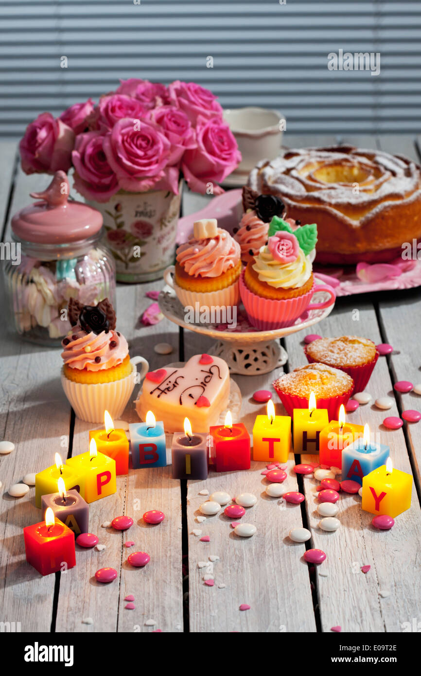 Muffins, birthday cake, cup cakes, roses, lighted birthday candles and