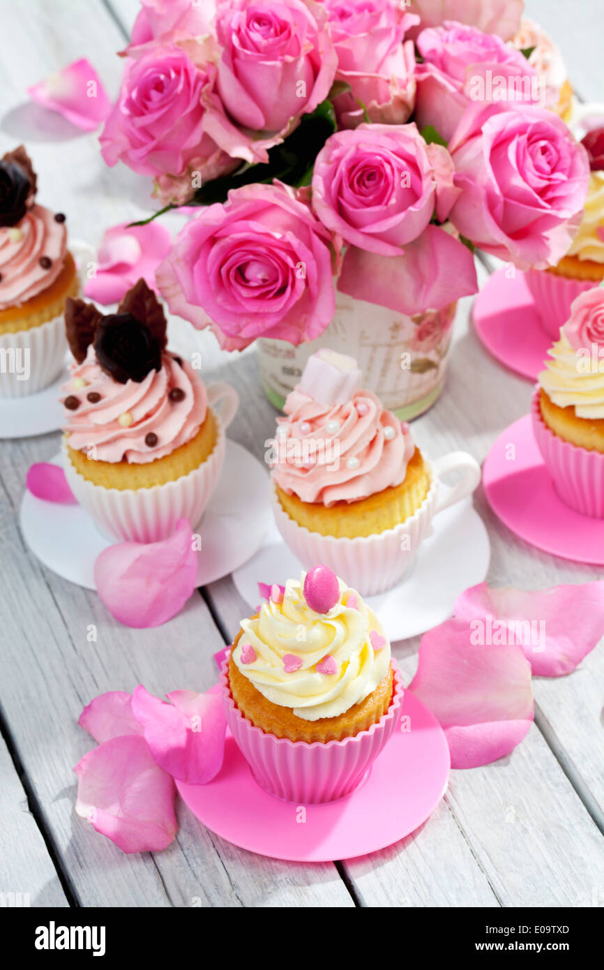 Cupcakes And Flower Vase Of Pink Roses On Wooden Table Stock Photo