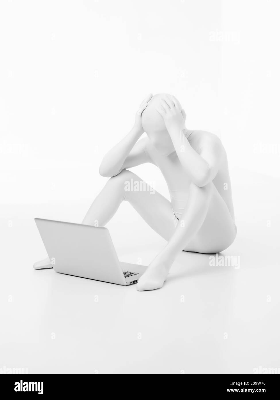 faceless man dressed in white sitting with a laptop on the floor with ...