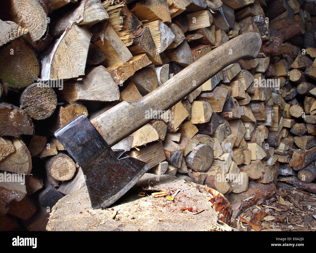Old ax in log on a firewood background Stock Photo
