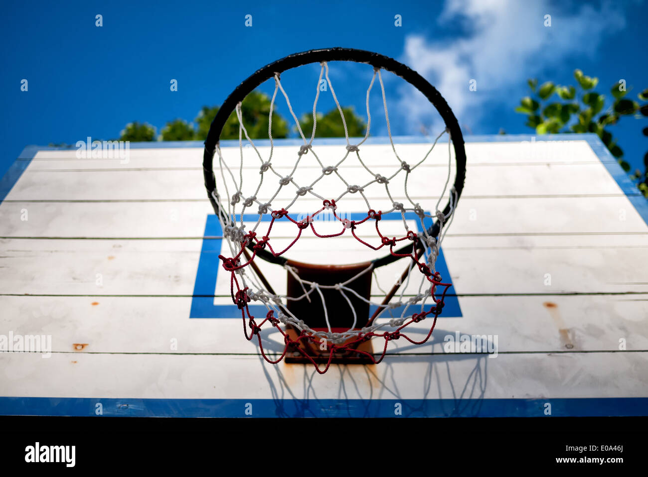 An old basketball backboard and rim under blue sky Stock Photo