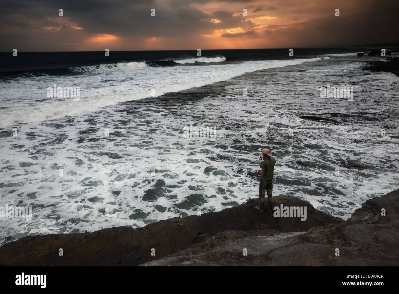 A Balinese man fishing on a cliff Stock Photo