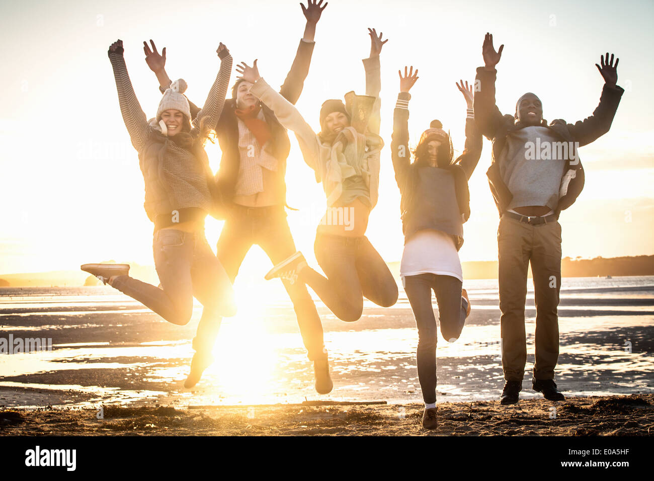 Five adult friends jumping mid air on the beach Stock Photo