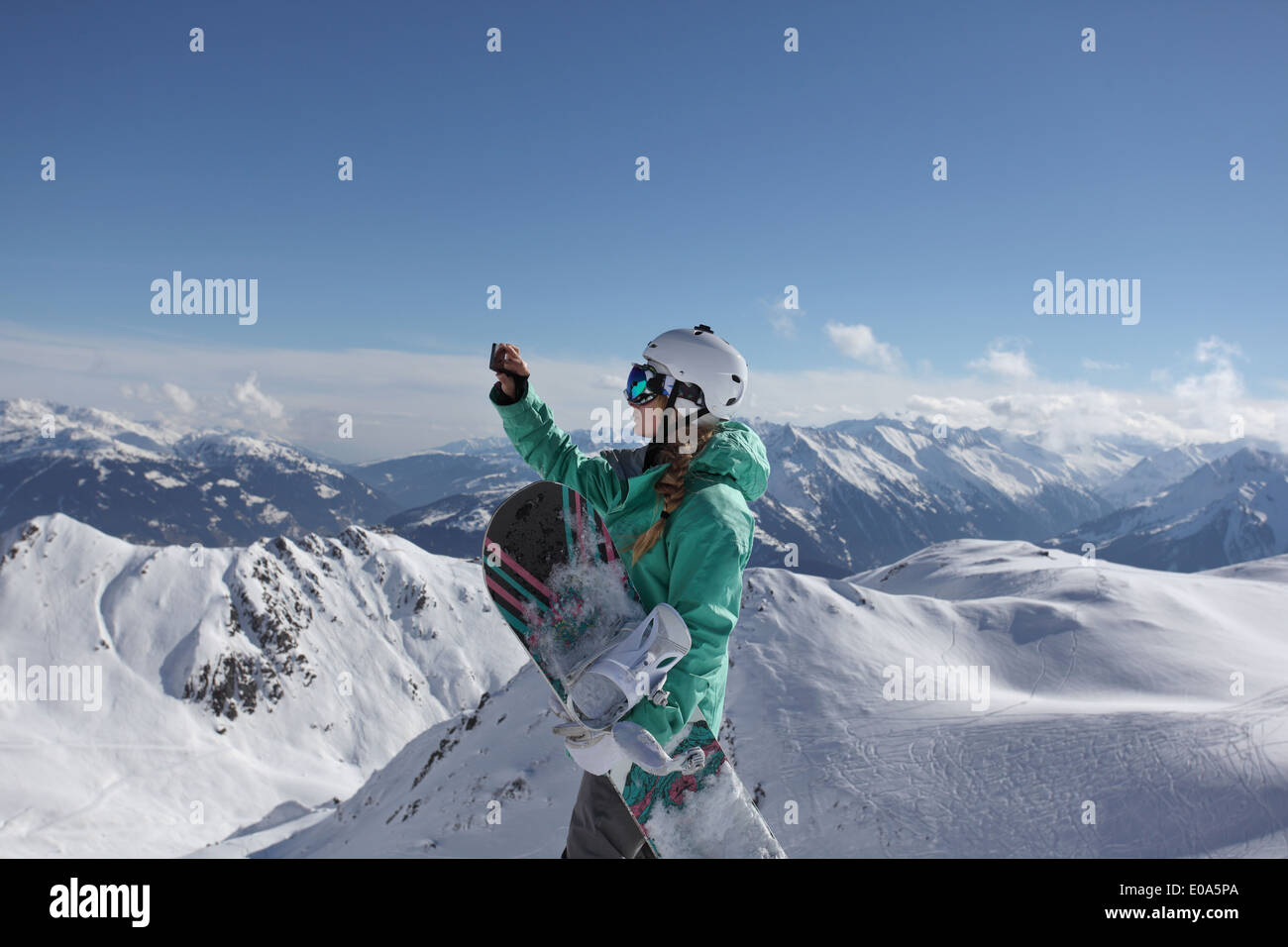 Young female snow boarder photographing mountain view, Mayrhofen, Tyrol, Austria Stock Photo