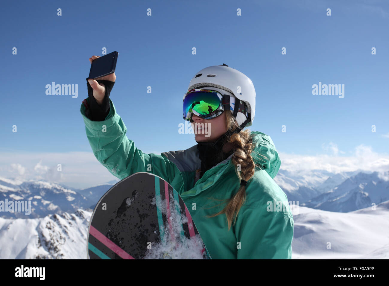 Young female snow boarder photographing view, Mayrhofen, Tyrol, Austria Stock Photo