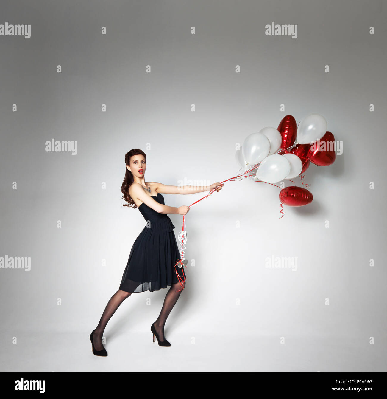 Woman pulling back escaping heartshaped balloons Stock Photo Alamy