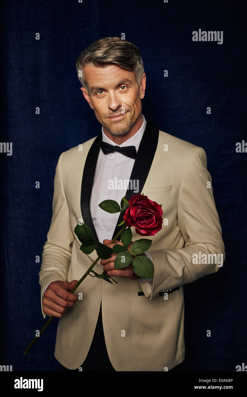 Man in tuxedo holding single rose Stock Photo