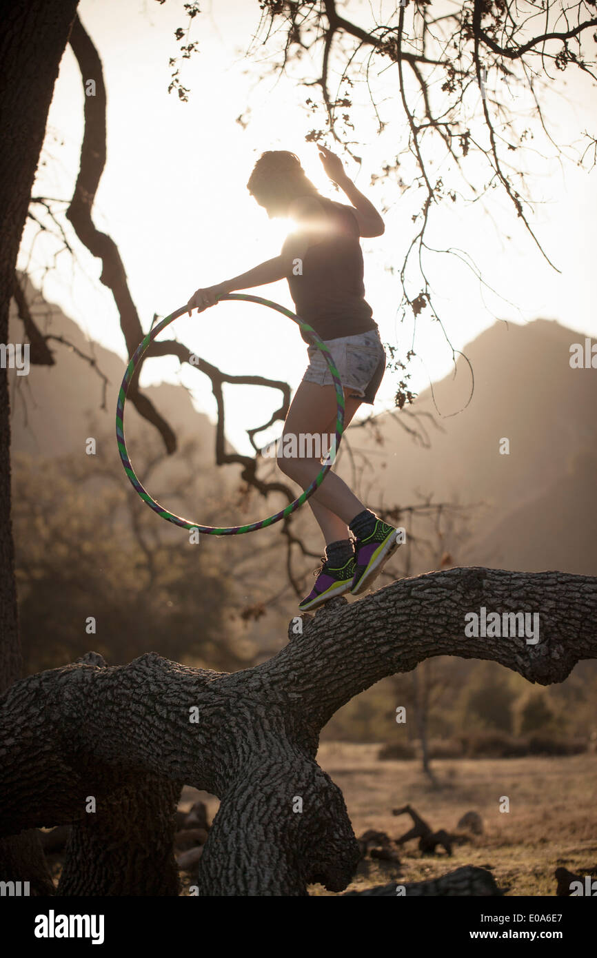 Young woman balancing on branch with hoola hoop, Malibu Creek State Park, California, USA Stock Photo