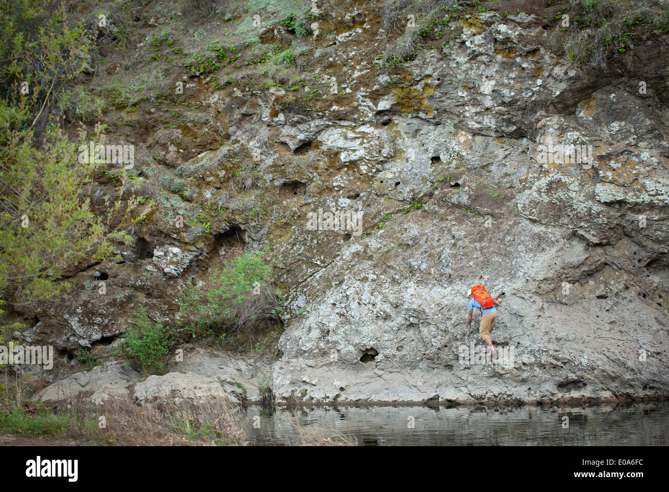 Young man climbing on lakeside rock, Malibu Creek State Park, California, USA Stock Photo
