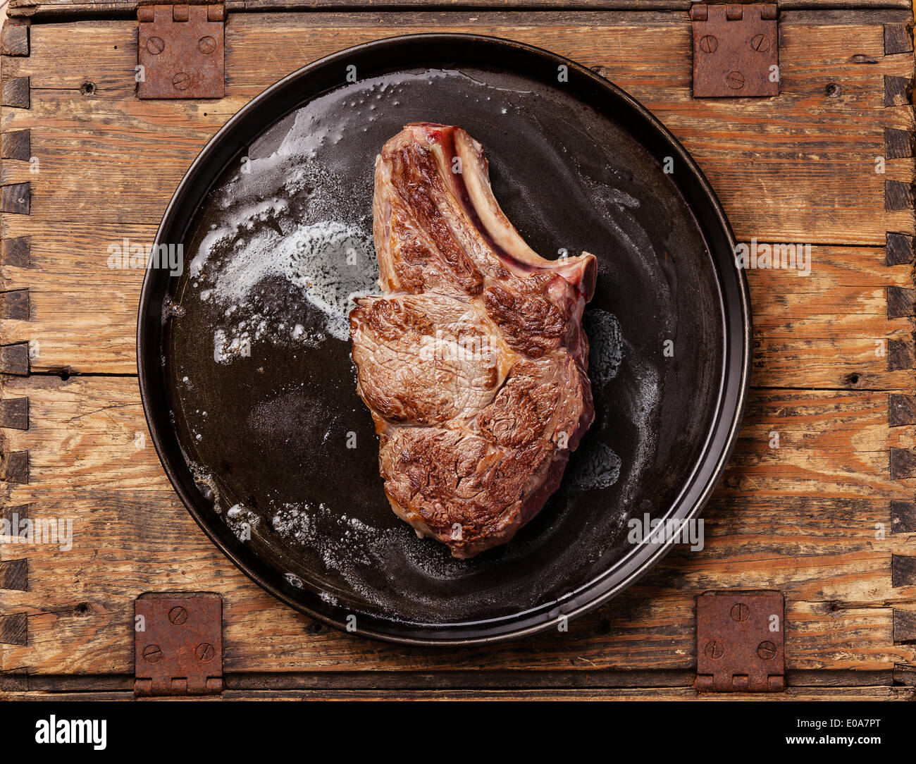 Veal cutlet with bone on pan on wooden background Stock Photo