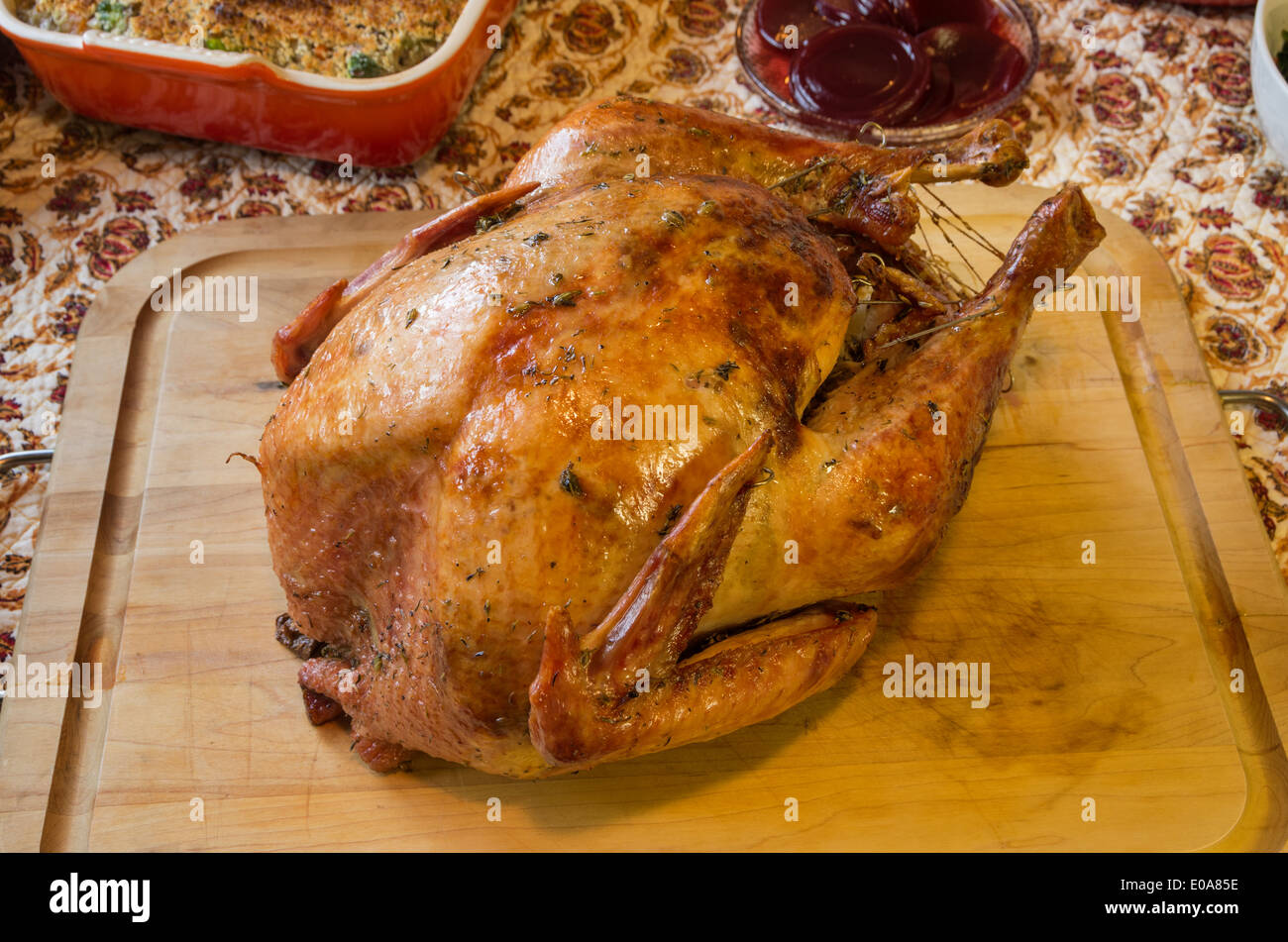 roast turkey on a wooden platter with some side dishes visible Stock Photo