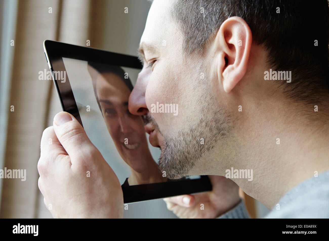 Mid adult man kissing screen of digital tablet Stock Photo