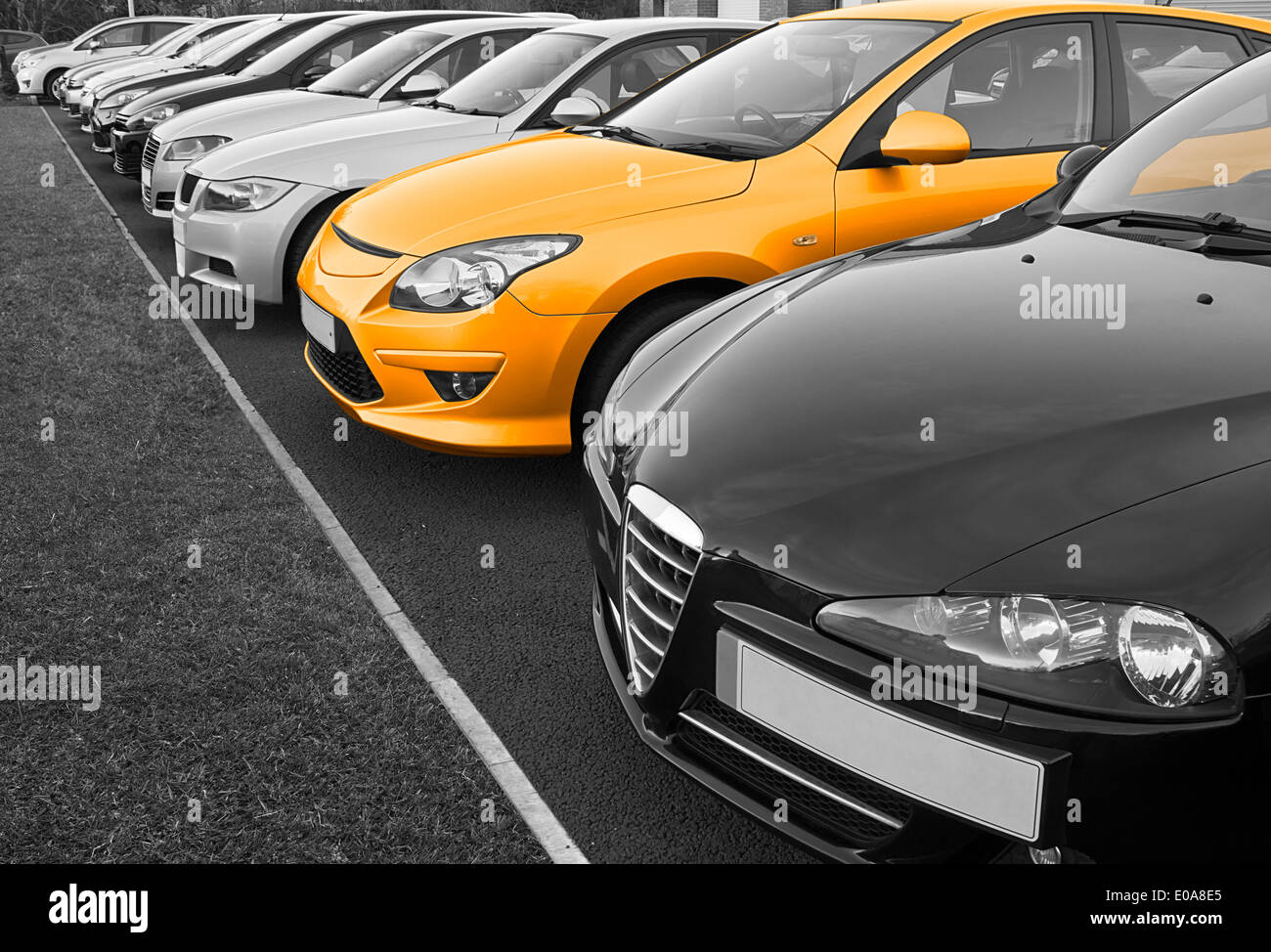 Row of used cars for sale in row with one in colour, great concept for choice of perfect vehicle to buy. Stock Photo