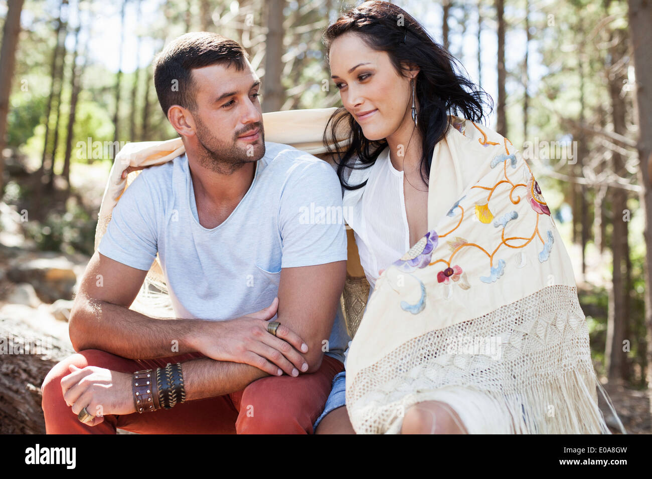 Young couple sitting in forest, arm around Stock Photo