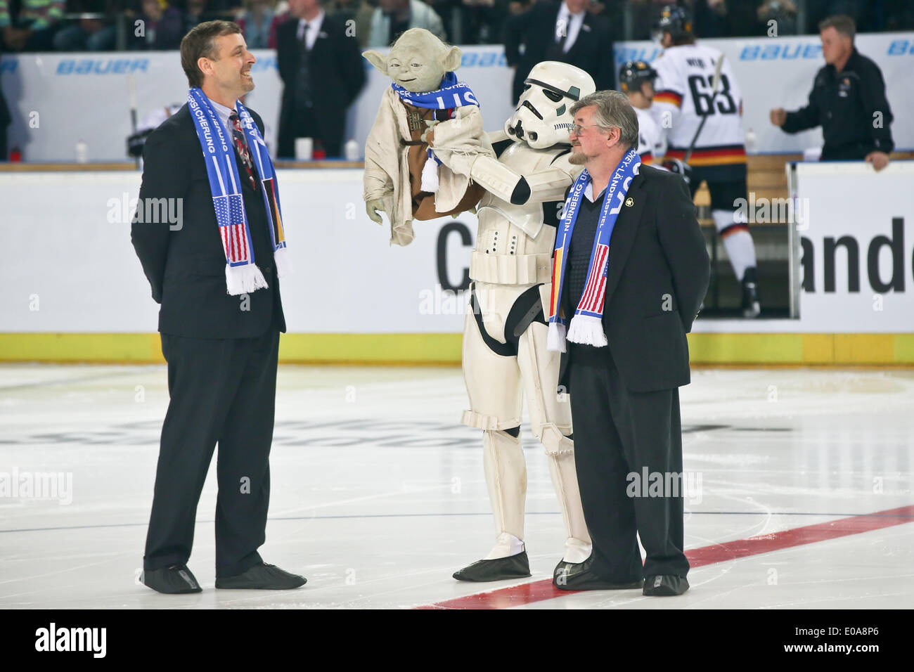 Nuremberg, Germany. 06th May, 2014. US consul general in Munich, Bill Moeller (L-R) stands on the ice with a man in a Star Wars Stormtrooper costume who holds up a Yoda Star Wars puppet and the inventor of the Yoda figure Nick Malesy prior to the ice hockey friendly match Germany vs USA in Nuremberg, Germany, 06 May 2014. Photo: DANIEL KARMANN/dpa/Alamy Live News Stock Photo