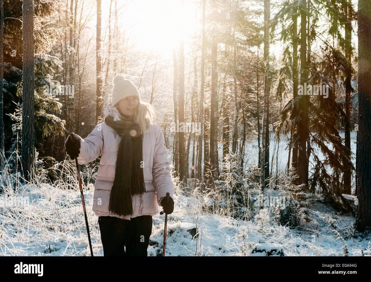 Mid adult woman nordic walking in snow covered forest Stock Photo