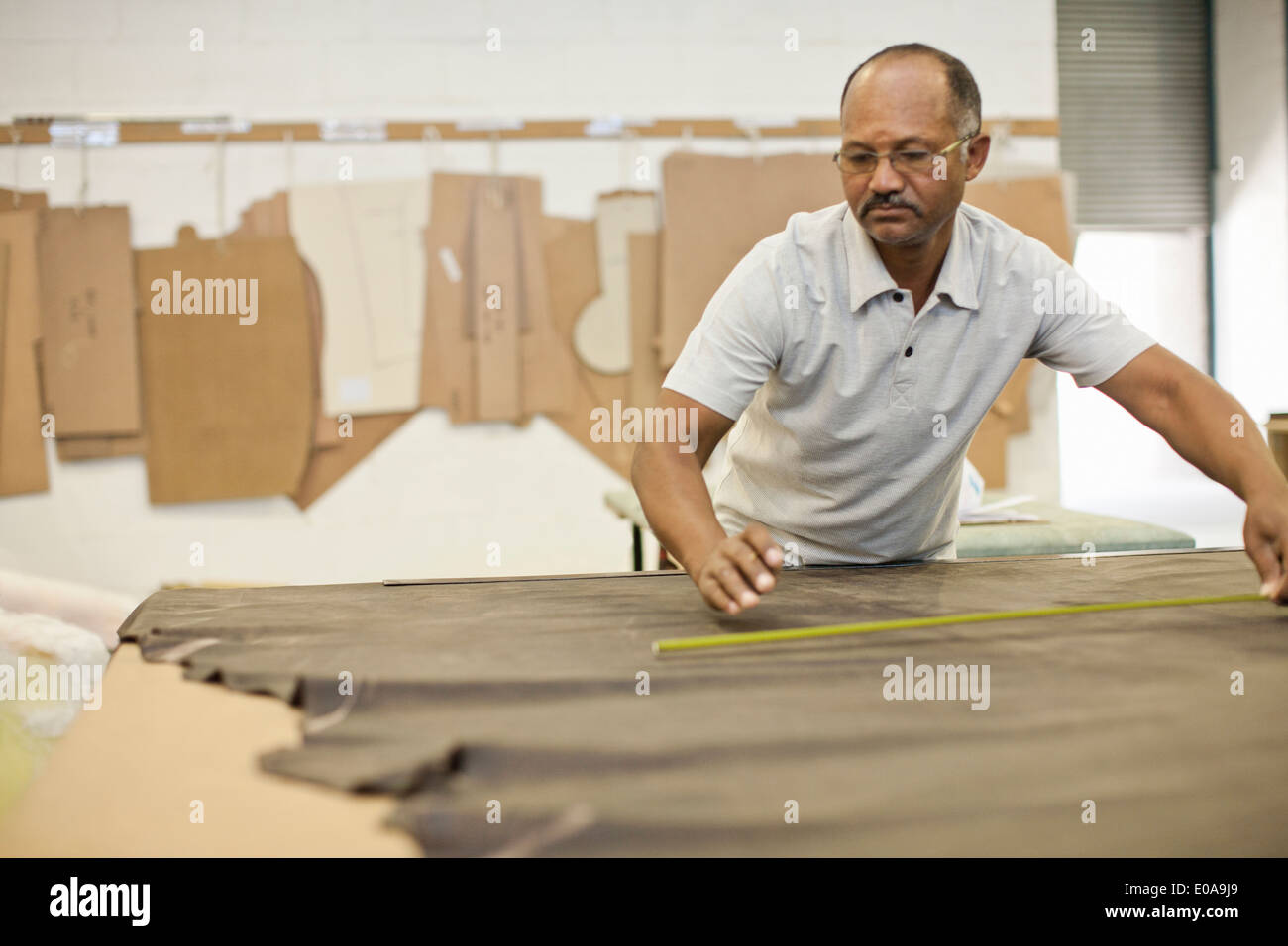 Upholsterer measuring leather on workbench Stock Photo