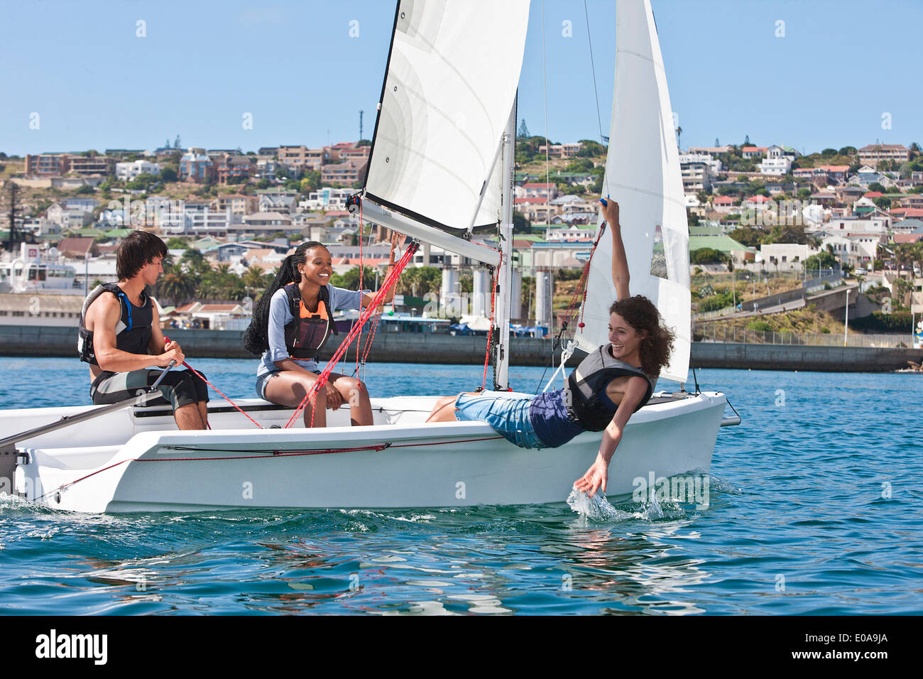 Three young friends sailing in harbor Stock Photo