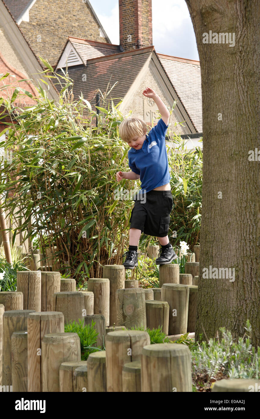School boy stepping on log fence Stock Photo