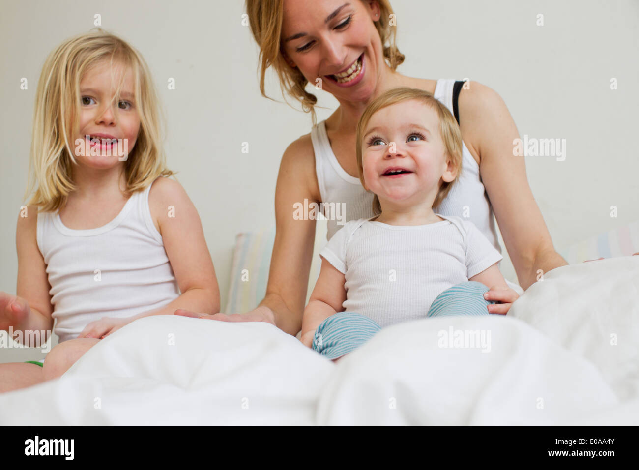 Portrait of mid adult woman in bed with two daughters Stock Photo