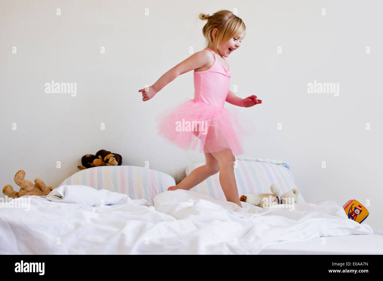 Girl dressed as ballet dancer running on bed Stock Photo