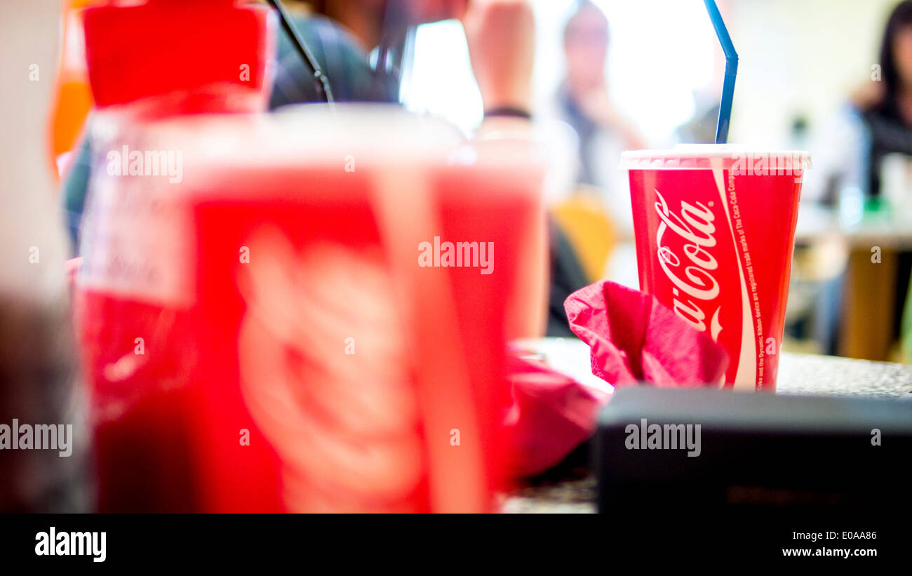 Cup of Take Away Coca-Cola Drink with Straw on Table in Restaurant. Stock Photo