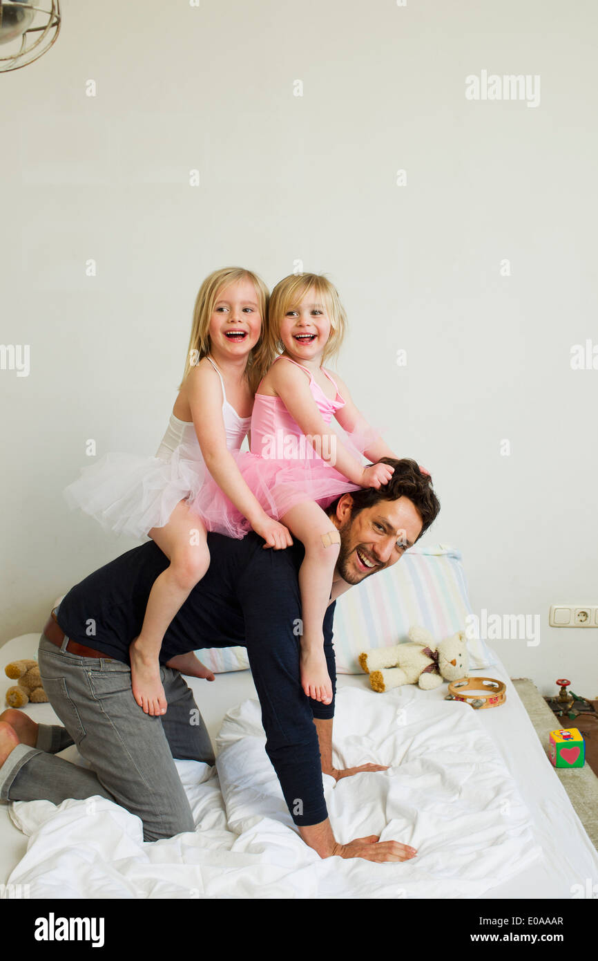 Portrait of mid adult father giving two young daughters a piggy back Stock Photo