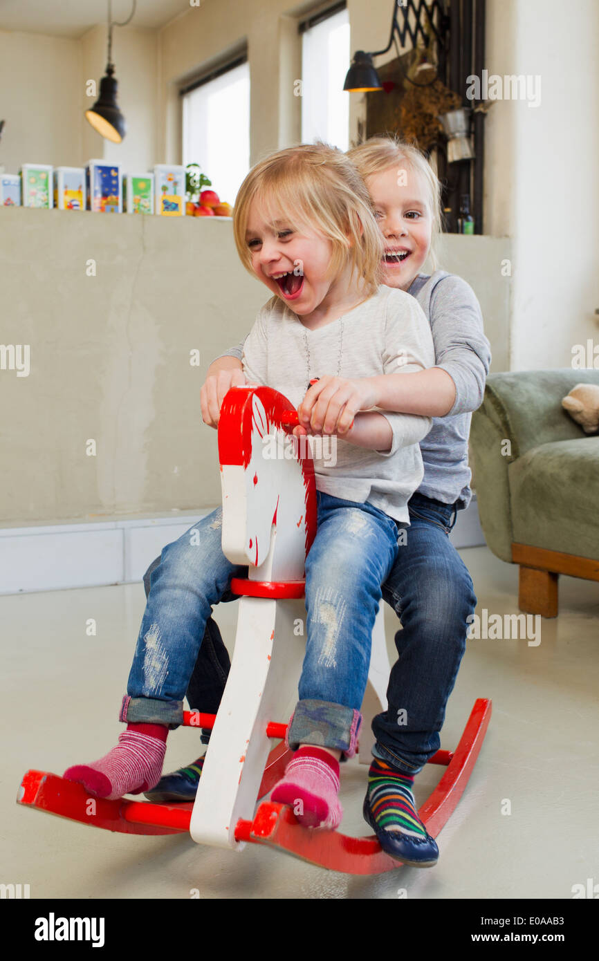 Two young sisters playing on rocking horse Stock Photo
