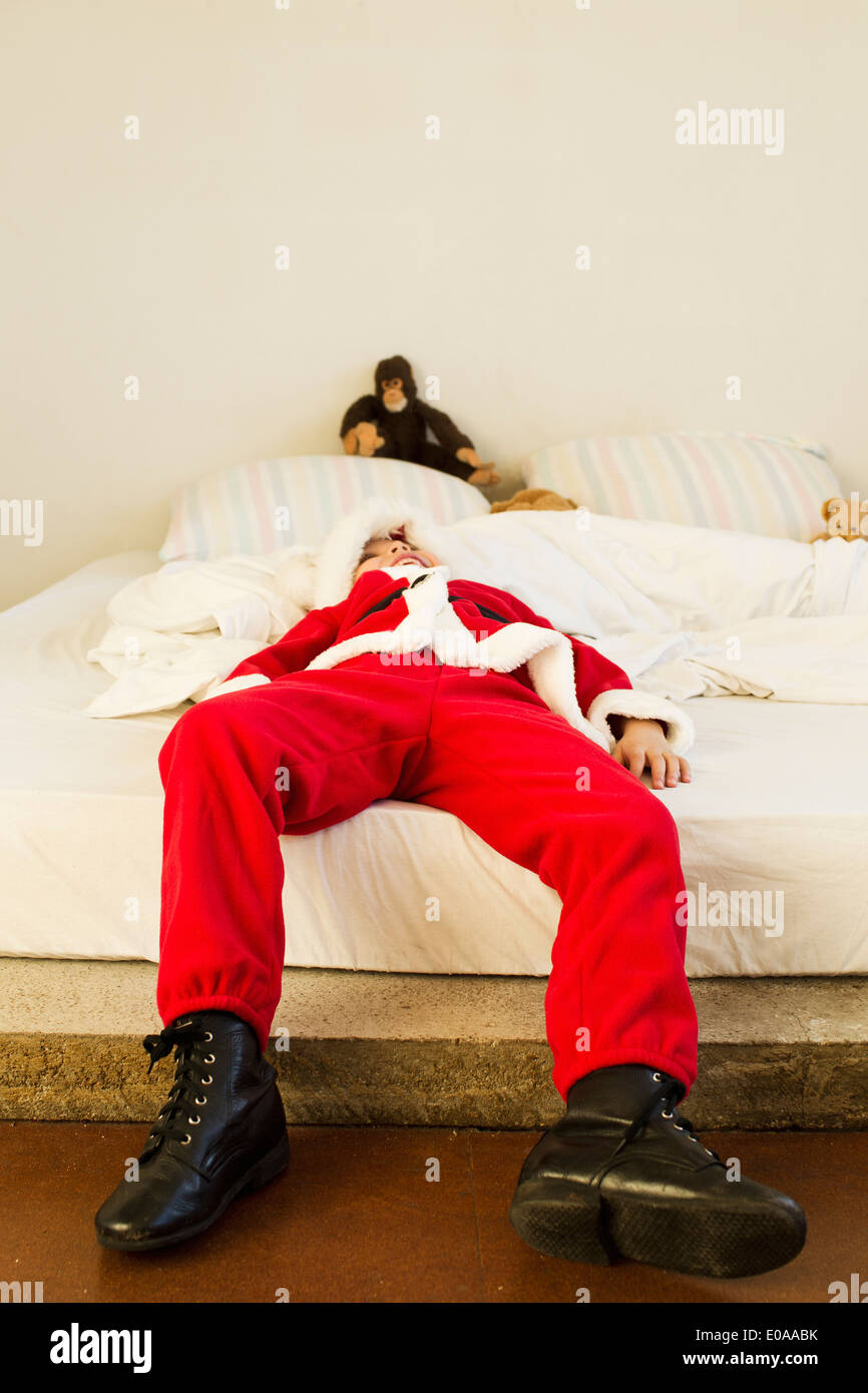 Young boy dressed up as santa claus lying on bed Stock Photo