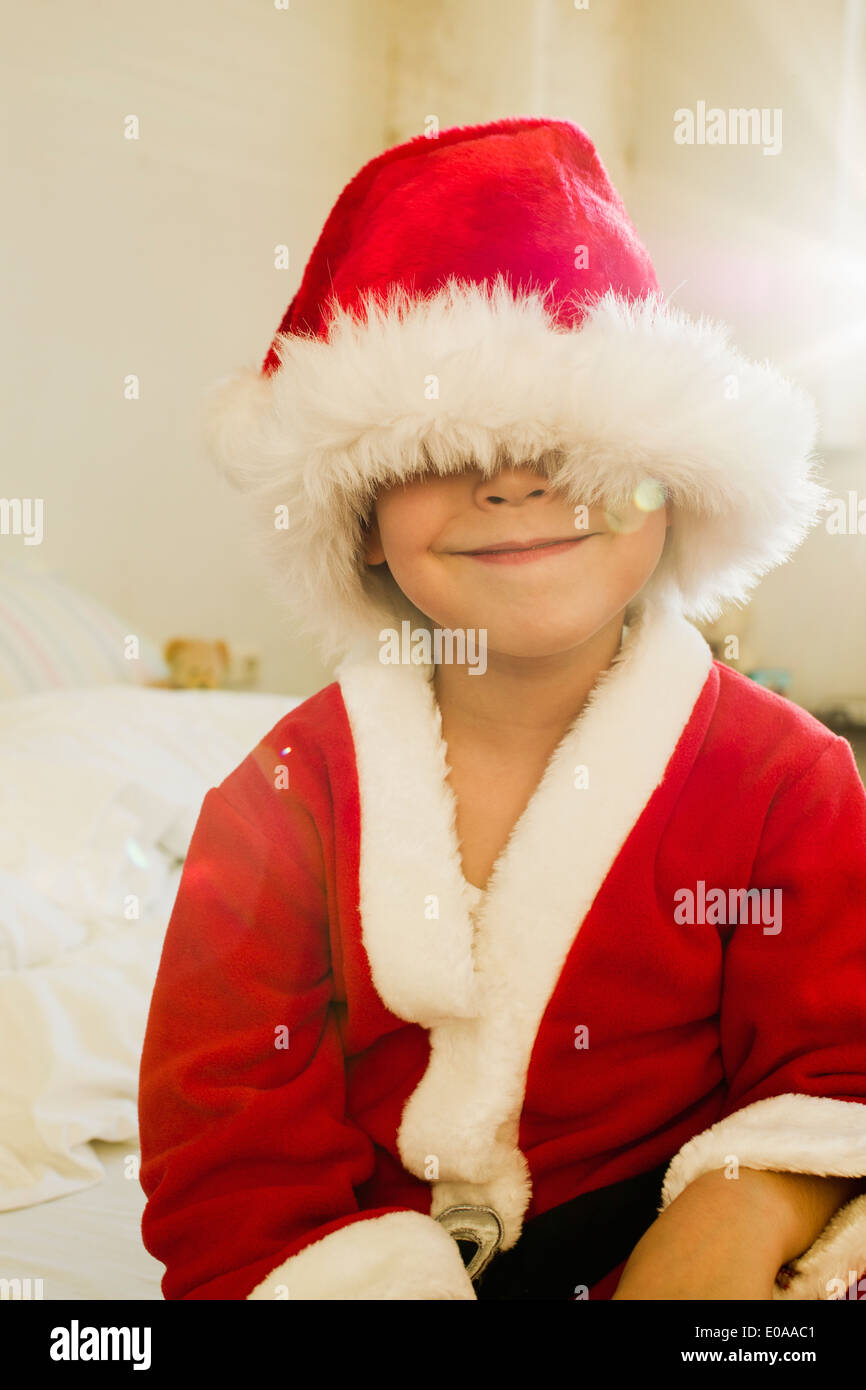 Portrait of young boy hidden by santa outfit cap Stock Photo