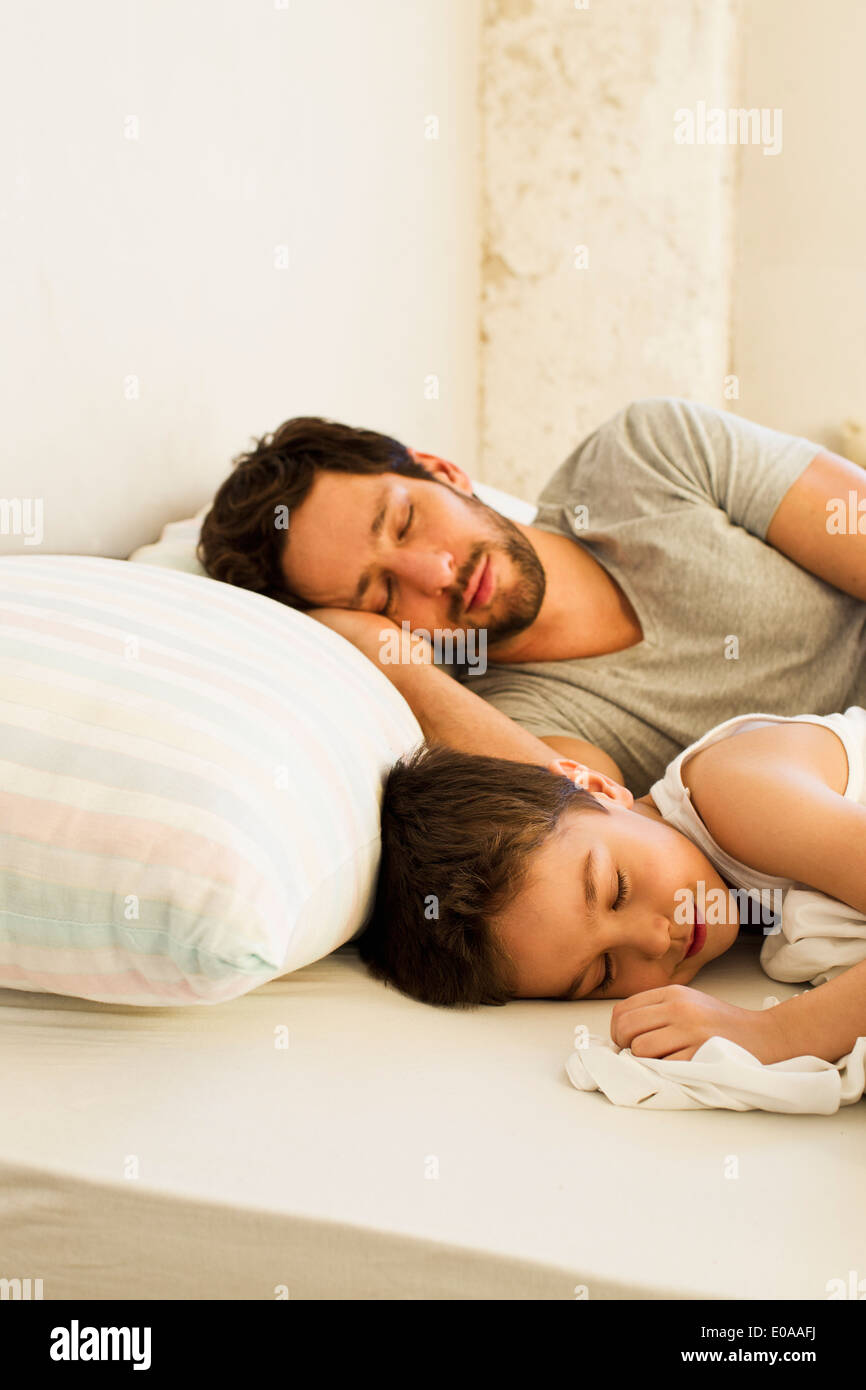 Father and young son asleep in bed Stock Photo